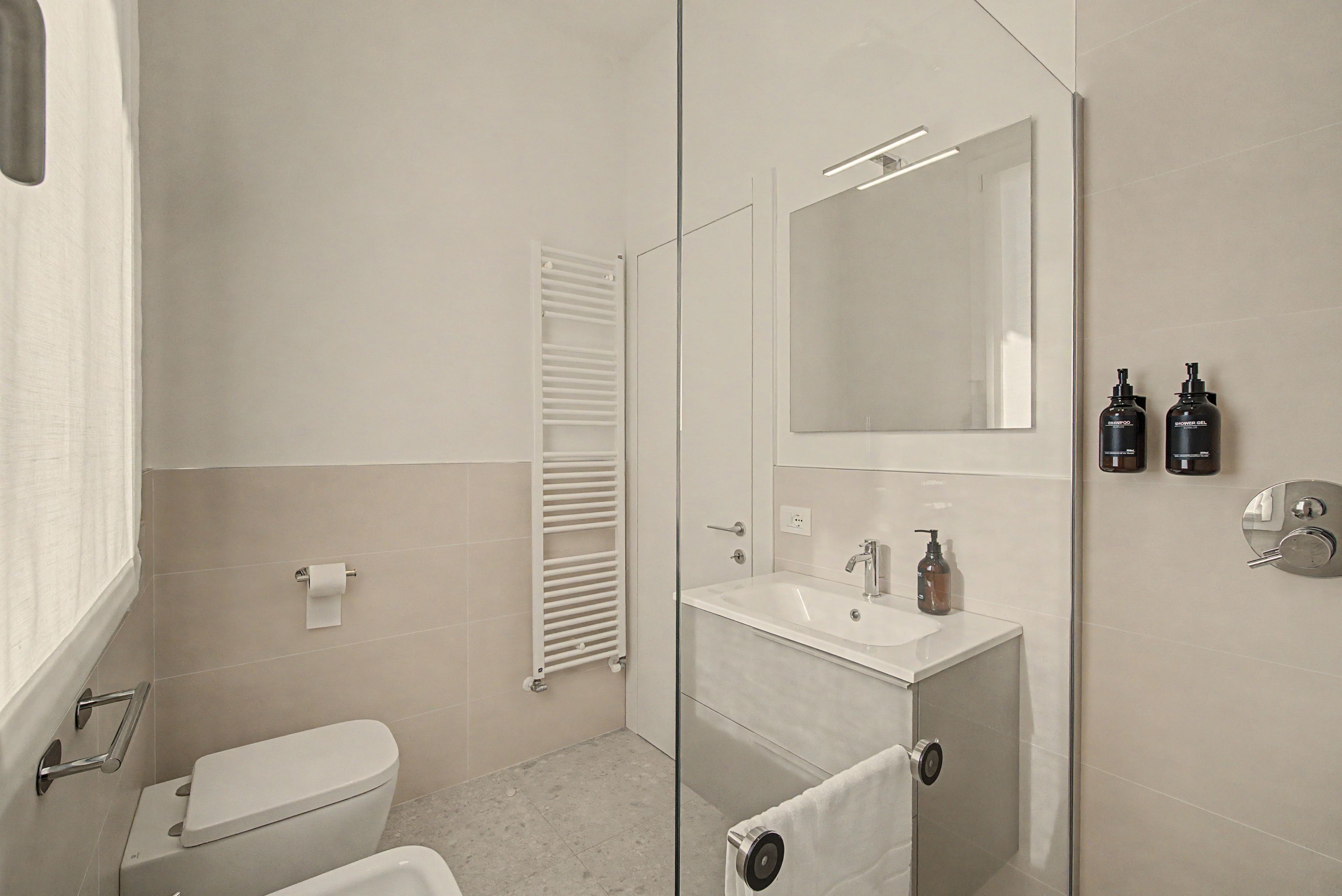 A modern bathroom with a toilet, sink, and mirror.