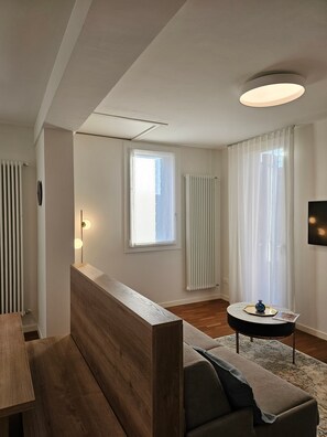 Ein modernes Wohnzimmer mit einer hölzernen Bank, einem runden Couchtisch, einer Couch und einem an der Wand befestigten Fernseher.