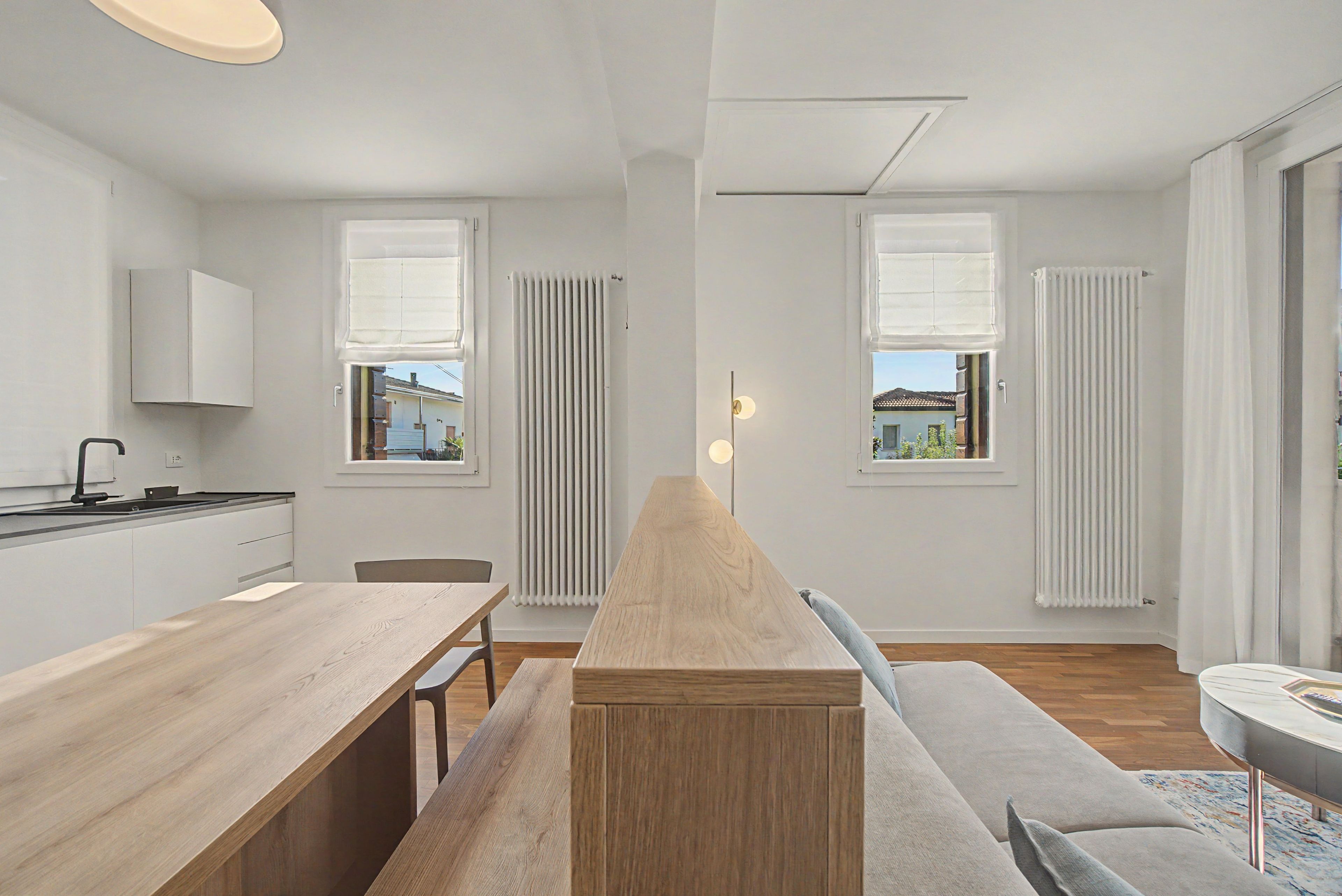 A modern kitchen with a central island, a dining area with a wooden table, and a seating area with a sofa.