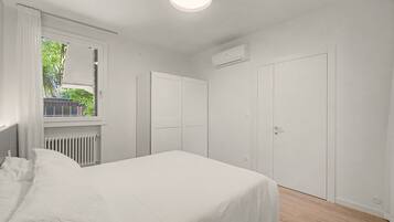 A bedroom with a bed, a window, a radiator, and a door.