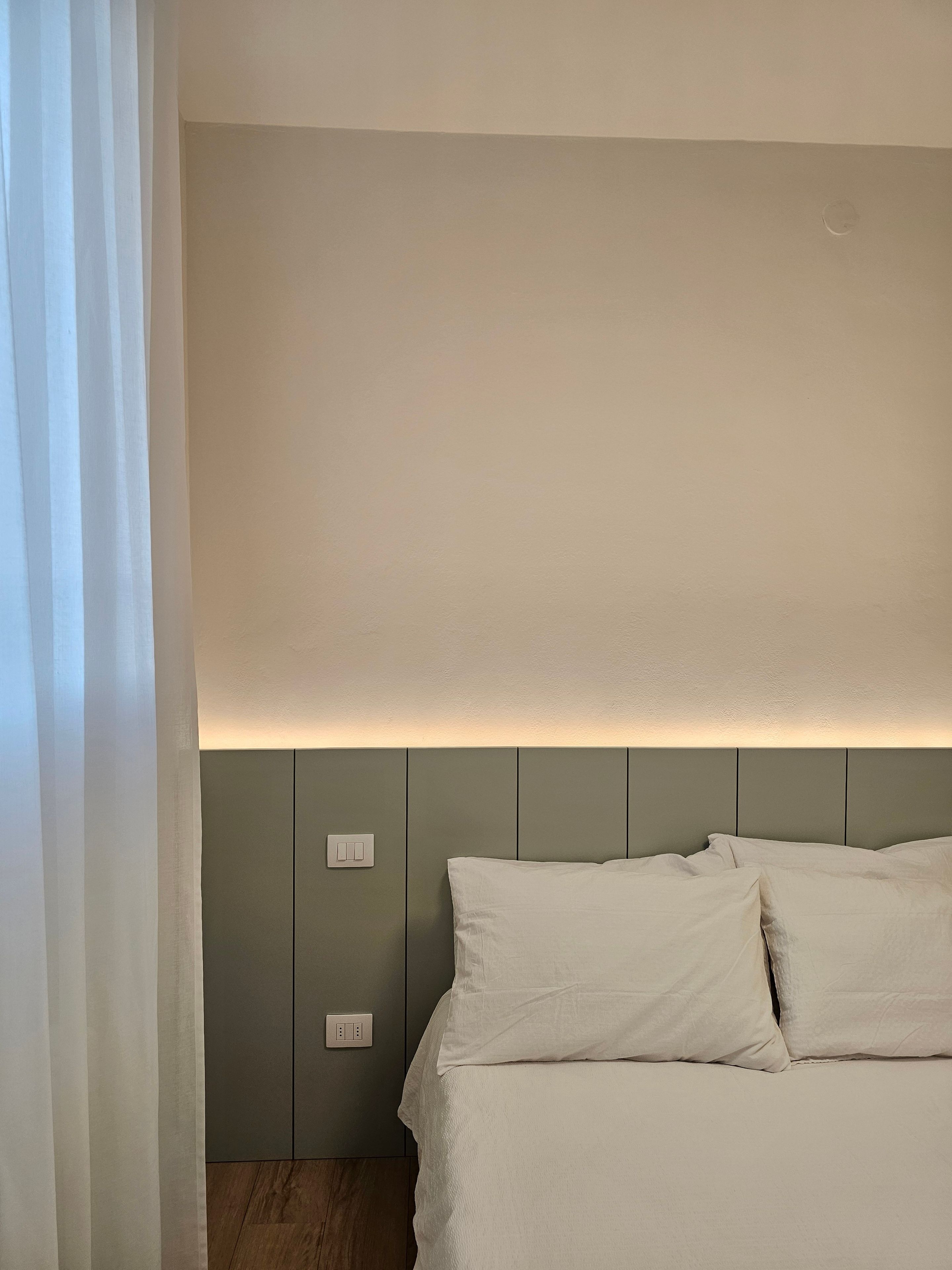 A bedroom with a bed, a nightstand, and a wall-mounted light fixture.
