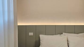 A bedroom with a bed, a nightstand, and a wall-mounted light fixture.