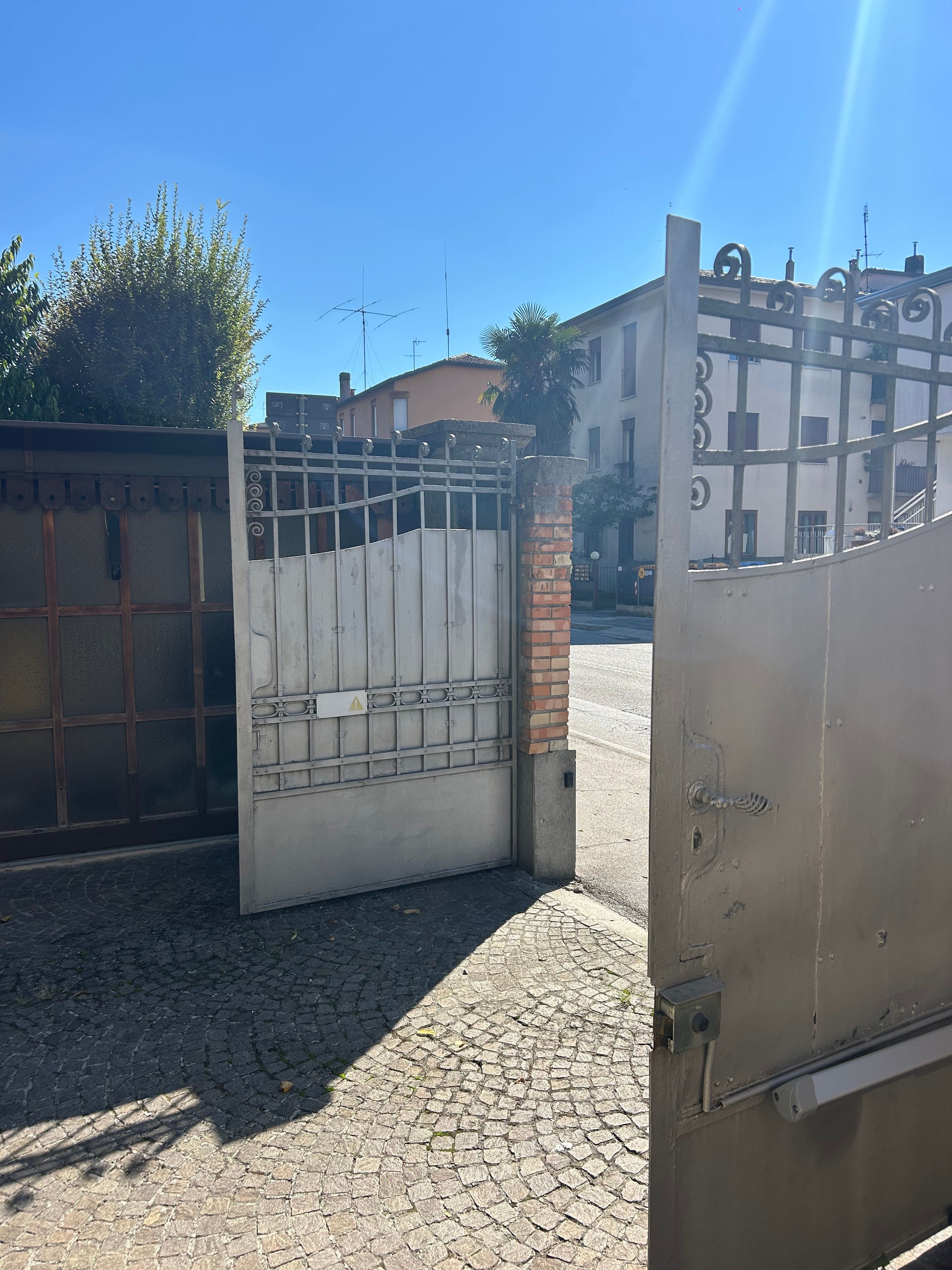 A gated entrance with a metal gate and a brick pillar.