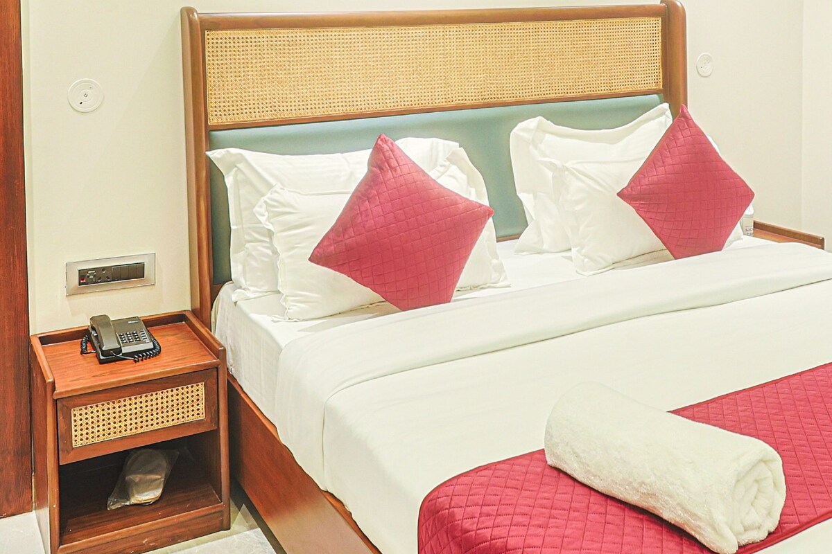 A hotel room with a bed, a bedside table with a phone, and a wall-mounted light fixture.
