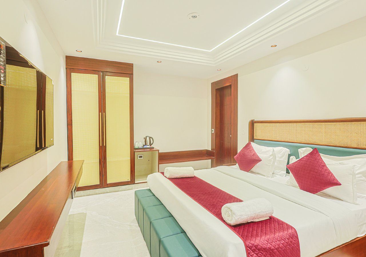 A hotel room with a bed, a bench, a small table, and a wardrobe.