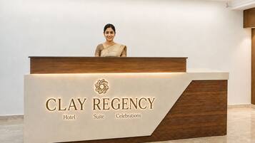 A reception desk at Clay Regency Hotel with a modern design, featuring a logo and the hotel's name.