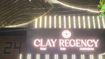 A hotel entrance with a large illuminated sign reading 'CLAY REGENCY Hotel Suite Celebrations'.