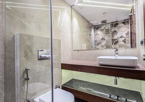 Et moderne badeværelse med en glasbrusekabine, et toiletbord med vask og et spejl.
