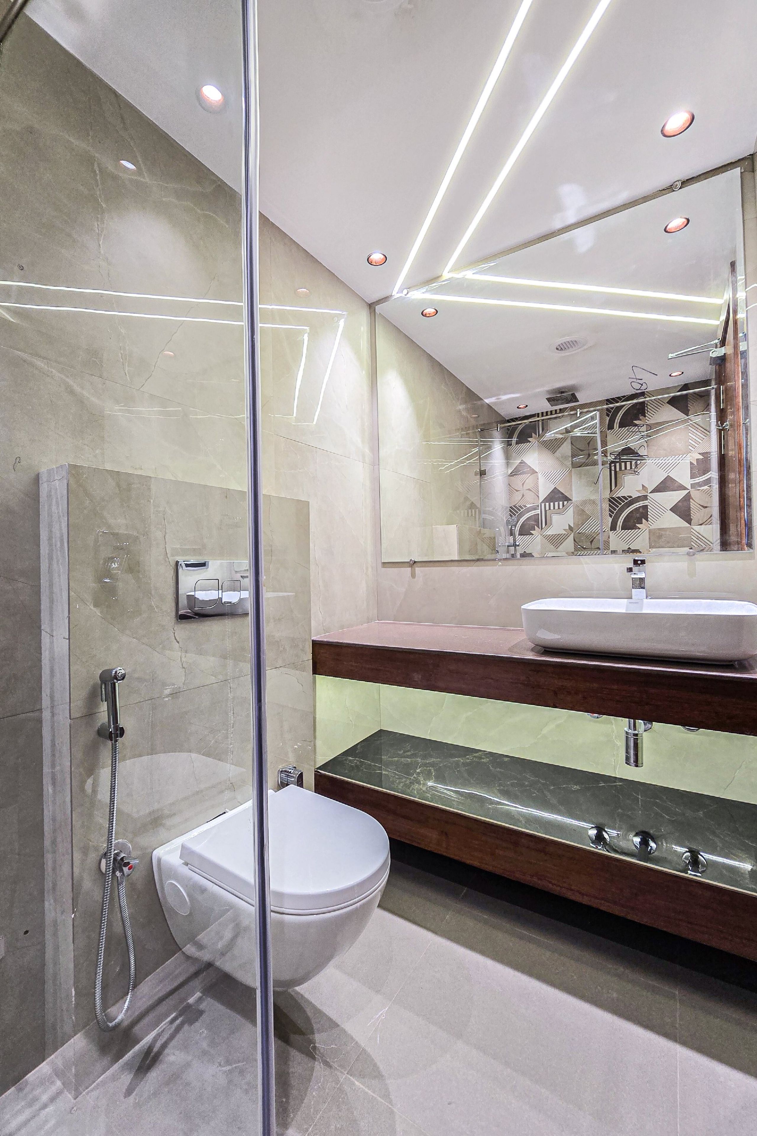 Un baño moderno con ducha acristalada, inodoro blanco y tocador con espejo.