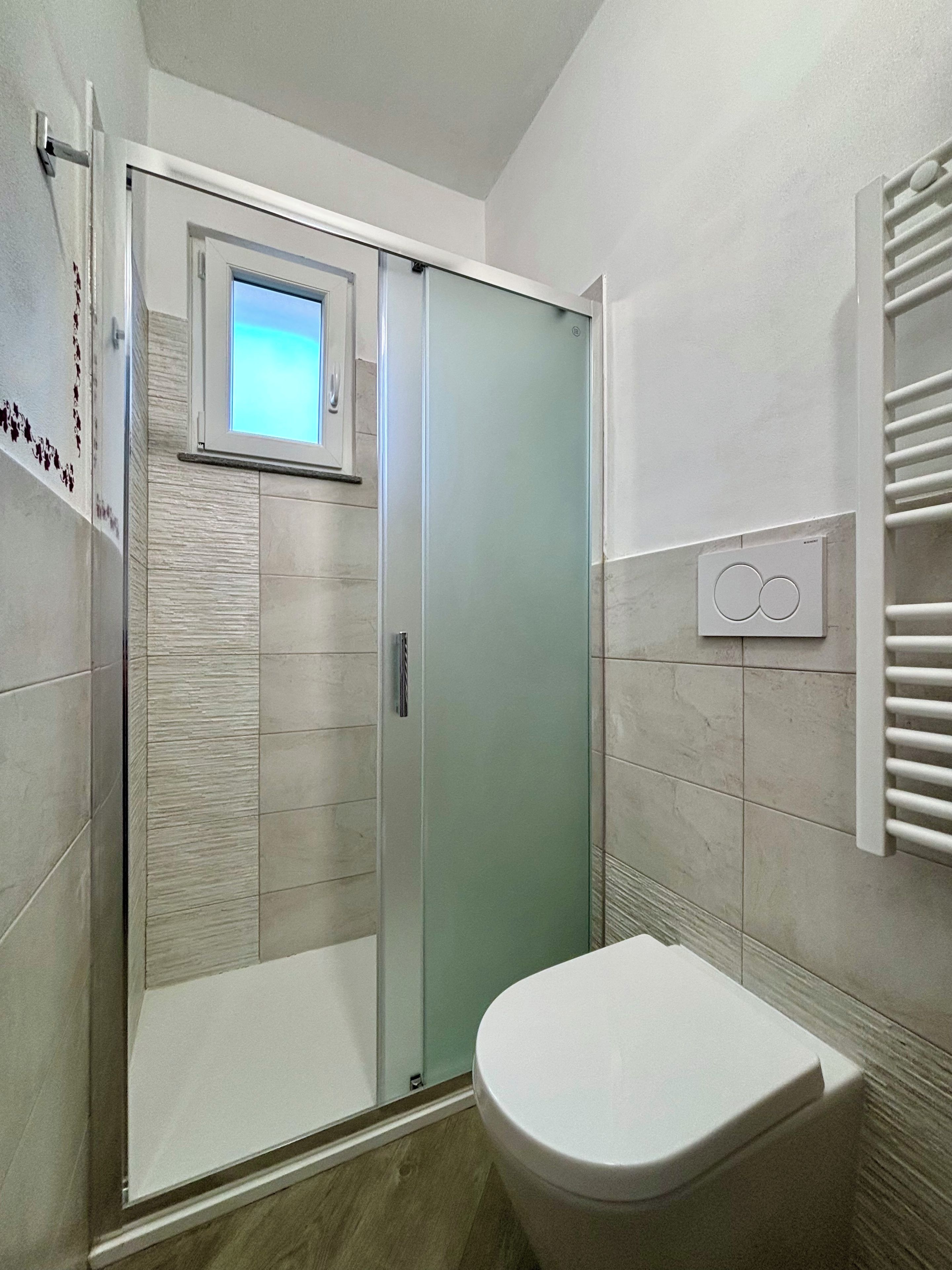 Ein modernes Badezimmer mit einer Duschkabine aus Glas, einer Toilette und einem Handtuchhalter.