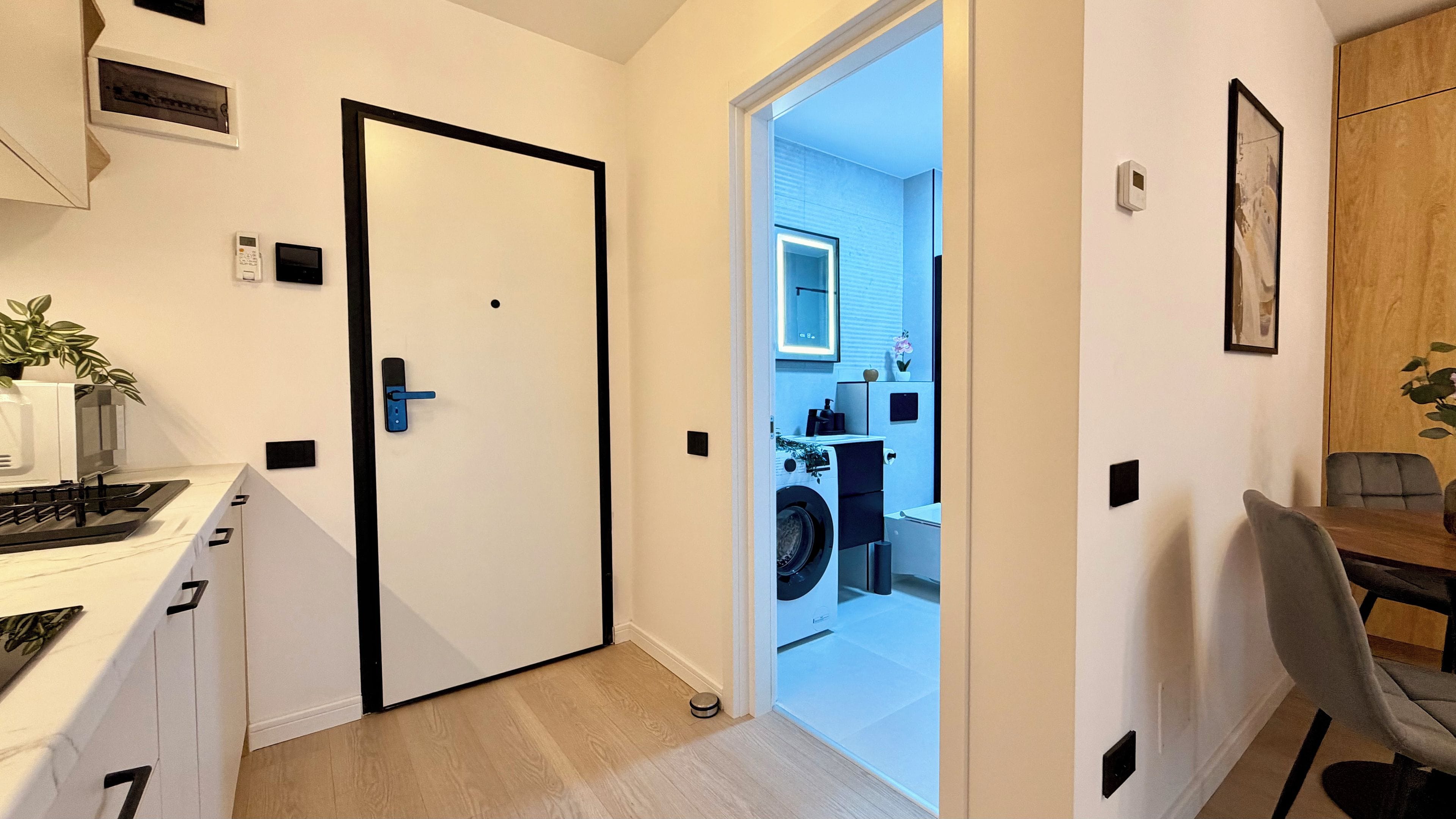 A modern kitchen with a built-in stove, a white cabinet, and a door leading to a laundry room with a washing machine.