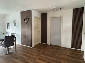 A room with a dining table and chairs, a door, and a wall with vertical slats. - New, Comfortable Vacation Rental for Families and Friends – 3 Minutes from the Beach (Bodman-Ludwigshafen)
