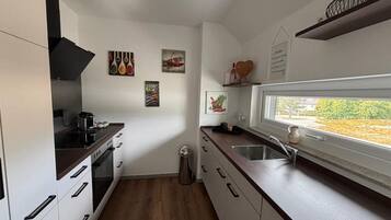 Une cuisine moderne avec des meubles blancs, un plan de travail en bois et une fenêtre offrant une vue agréable.