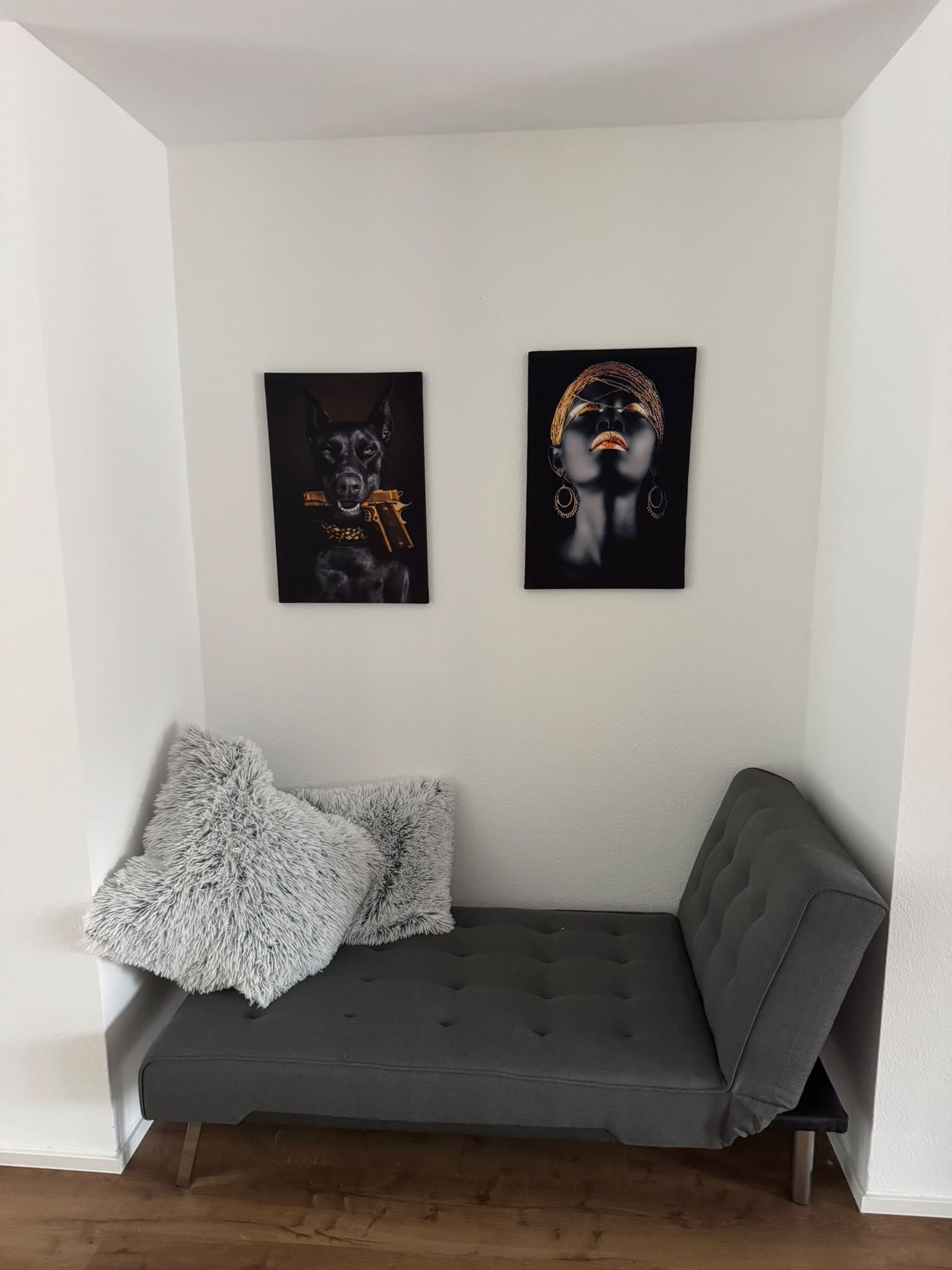 Un canapé gris agrémenté de deux coussins moelleux et de deux œuvres d’art encadrées accrochées au mur.