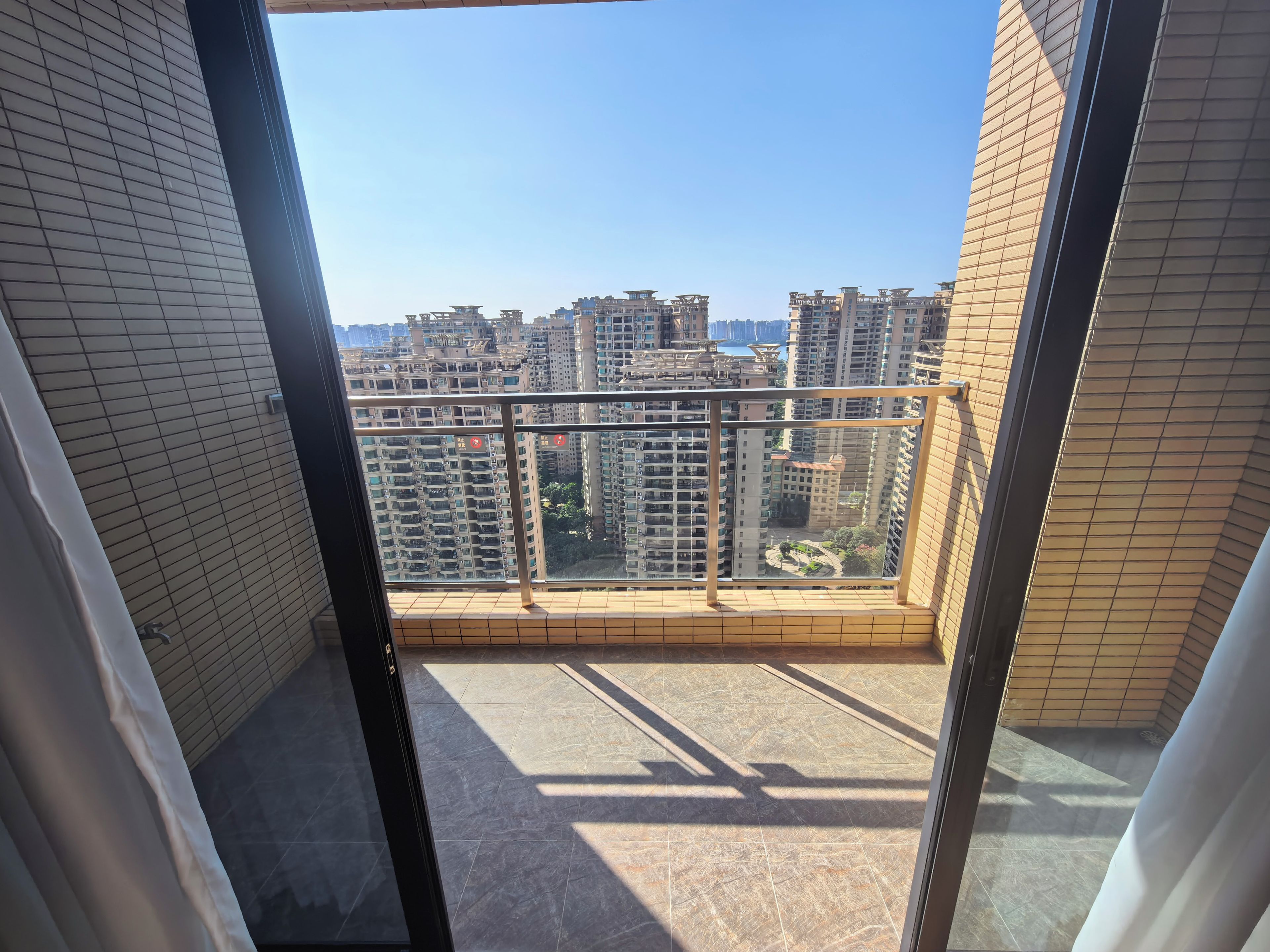 Ein Balkon mit Blick auf hohe Gebäude und einen klaren Himmel.