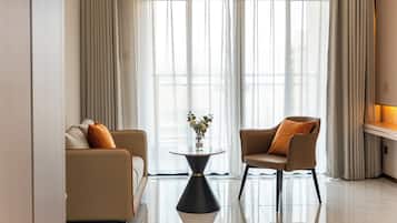 Una sala de estar moderna con un sofá, un sillón y una pequeña mesa redonda con un jarrón de flores.