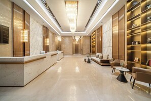 A hotel lobby with a reception desk, seating area, and a bookshelf. - Poltton International ApartmentsQingyuan (Qingyuan)