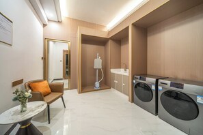 Ein Hotelzimmer mit einer Sitzecke, einer Waschmaschine und einem Spiegel.