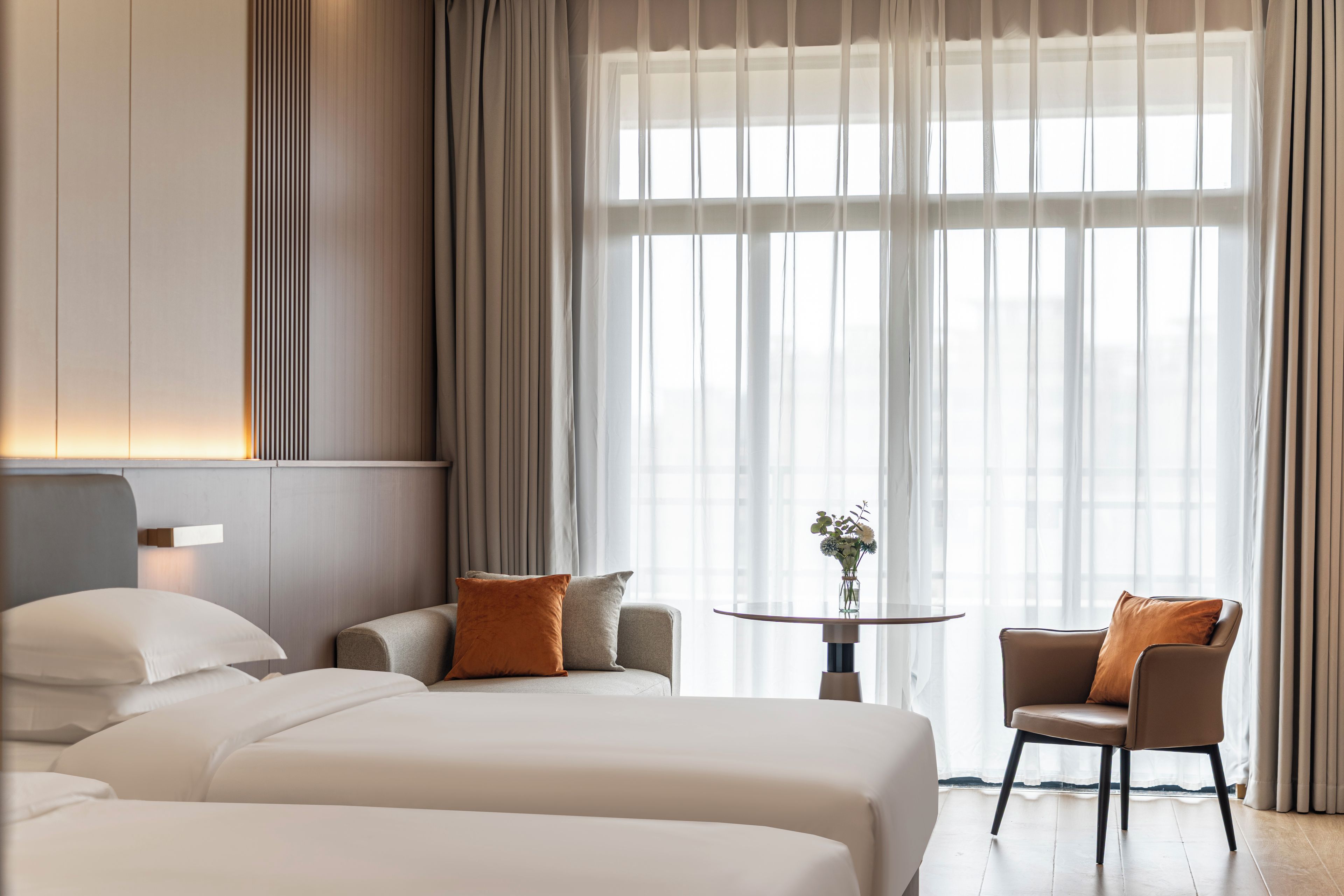 Habitació d'hotel amb dos llits, una taula petita amb un vas i una cadira.