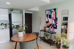 A modern kitchen with white cabinets, a wooden dining table, and a variety of potted plants. - Boutique studio in the heart of SJO with panoramic views & parking (San José)