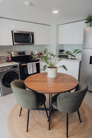 Una cocina moderna con comedor, que incluye microondas, horno y lavabo.