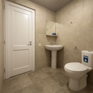 Un bagno con una porta bianca, un lavandino su piedistallo, un water e un cestino della spazzatura blu.