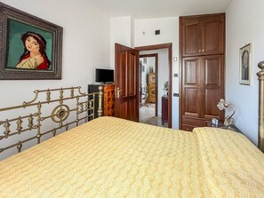 Ein Schlafzimmer mit einem Bett, einem Holzschrank, einem Schreibtisch mit Lampe und einem Bild an der Wand.