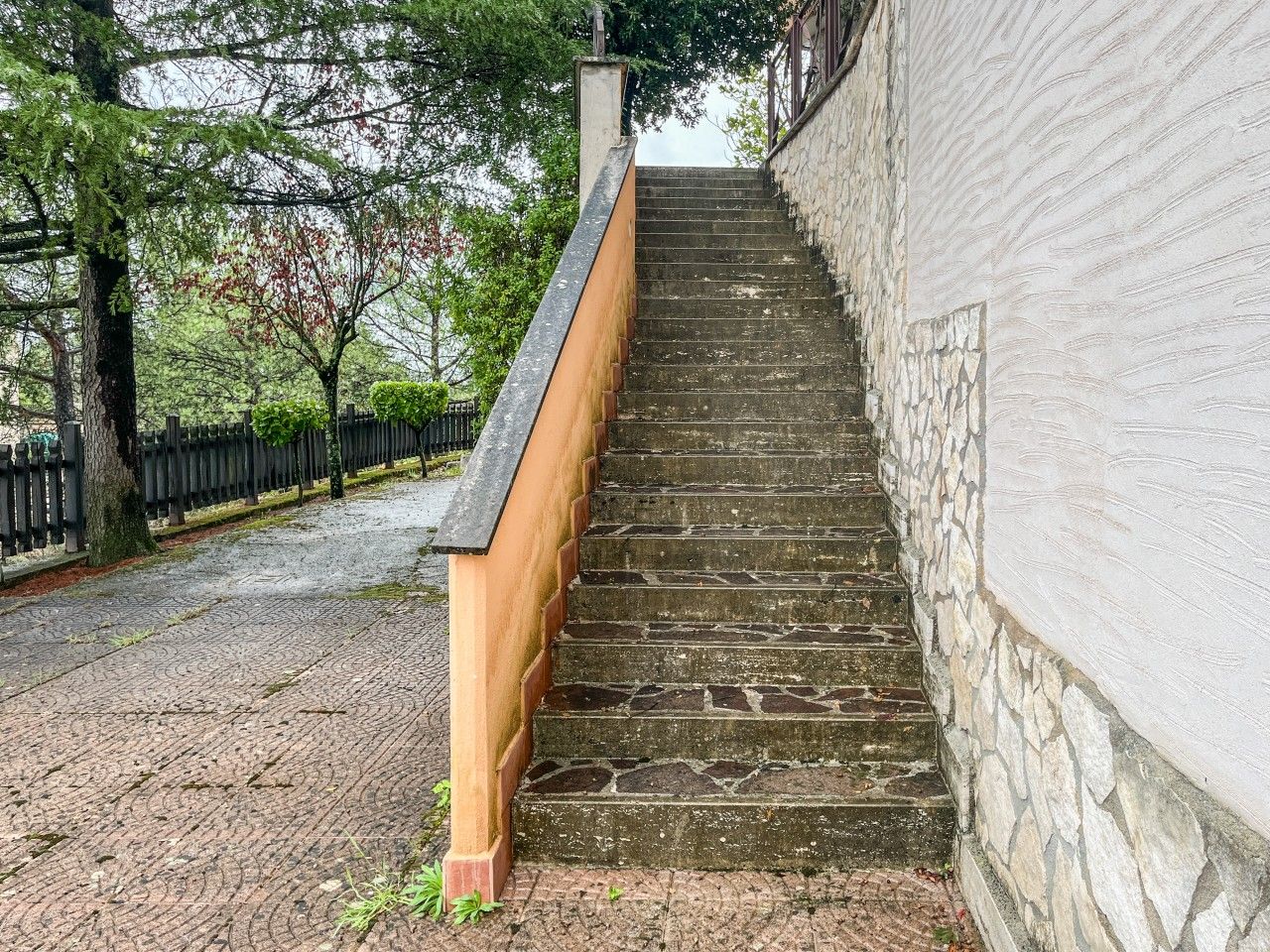 A set of stone steps leading up to a building with a white wall.