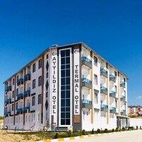 Un hotel de varios pisos con balcones, un letrero vertical en el centro y un cielo despejado.