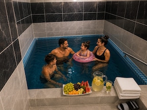 A family in a small, tiled hot tub with a fruit platter and drinks. - KILAS GÖZDE APART OTEL (İhsaniye)