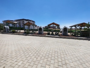 Un área pavimentada con mesas al aire libre y un edificio al fondo.