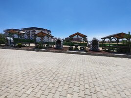 Un área pavimentada con mesas al aire libre y un edificio al fondo.