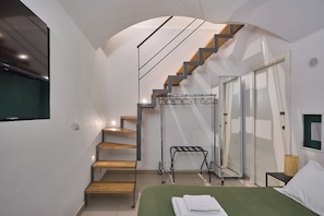 A modern bedroom with a wooden staircase, a bed with green bedding, a hanging coat rack, and a TV mounted on the wall. - A comfortable stay, easy self-check-in, and a great location for exploring Florence. (Firenze)