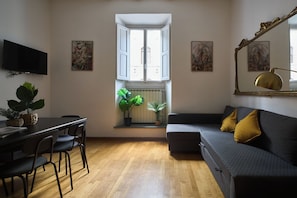 A modern living room with a dining area, a sofa with cushions, a television, and artwork on the walls. - A comfortable stay, easy self-check-in, and a great location for exploring Florence. (Firenze)