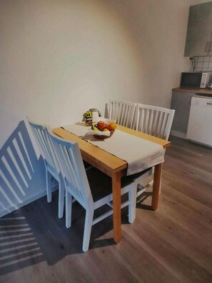 A dining area with a wooden table, white chairs, and a fruit bowl. - Northern Lights Apt Midtgaard · 2BR · Free Parking · Kvaløya Tromsø (Tromsø)