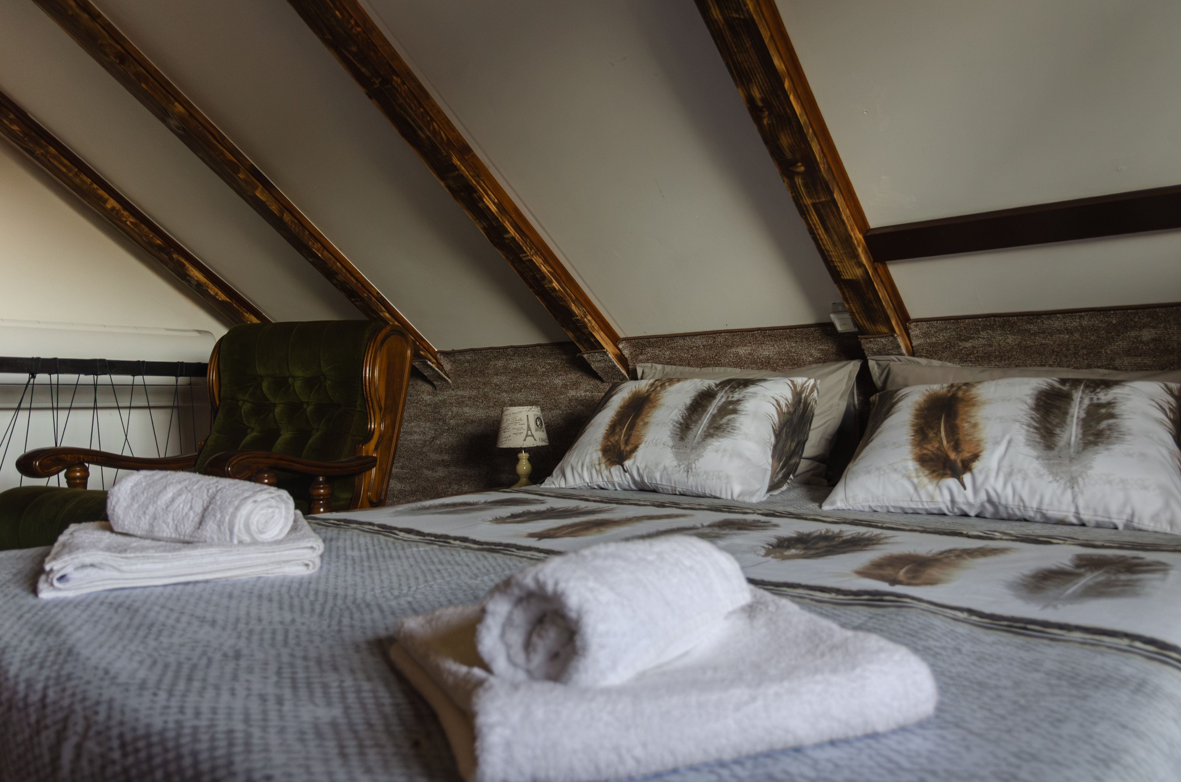 Habitación de hotel con cama, una silla, una lámpara y una toalla doblada con cuidado sobre la cama.