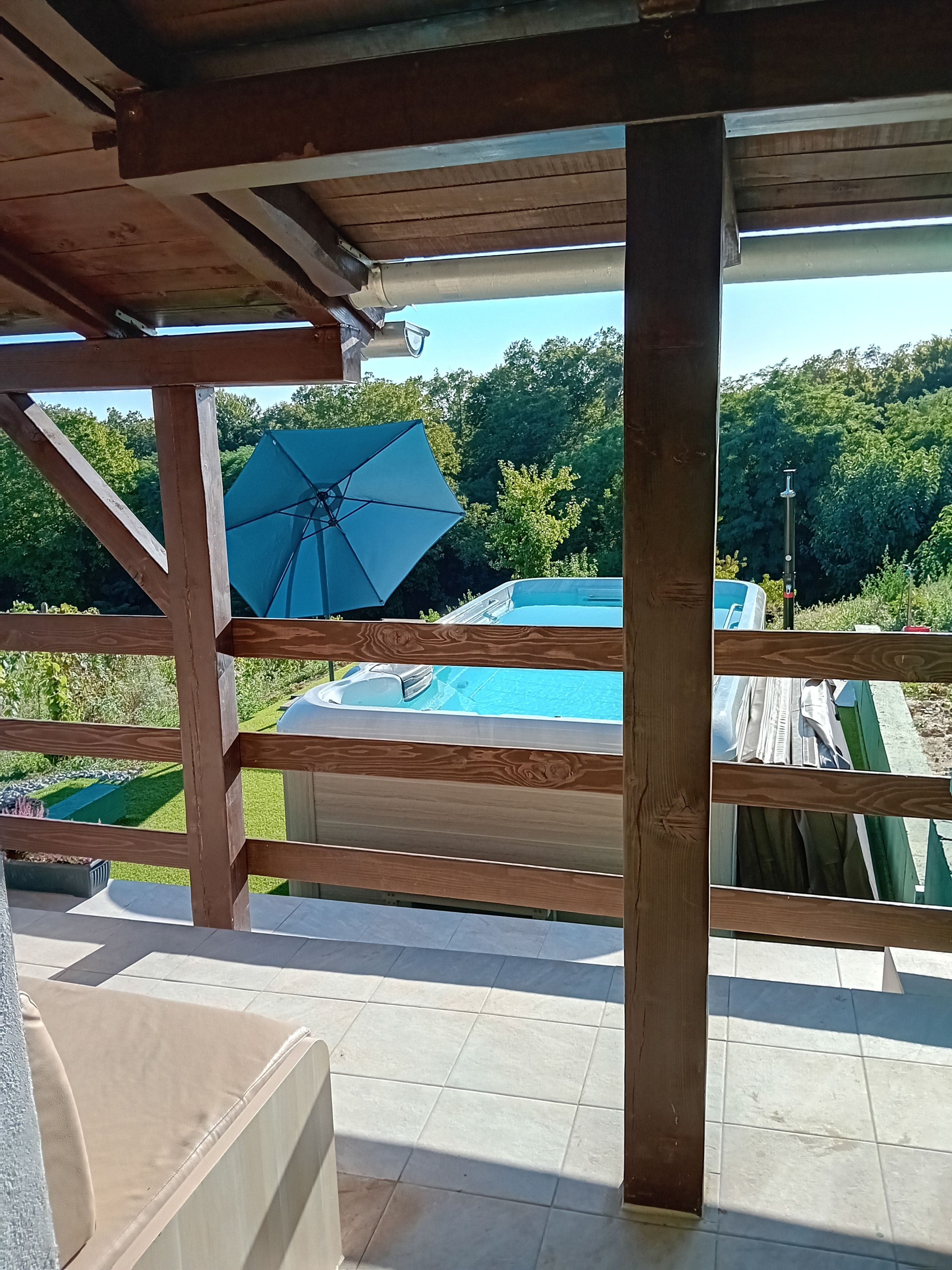 A wooden deck with a view of a swimming pool and greenery.