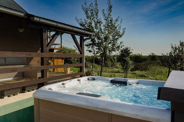 A hot tub with a wooden deck and a view of the surrounding landscape.