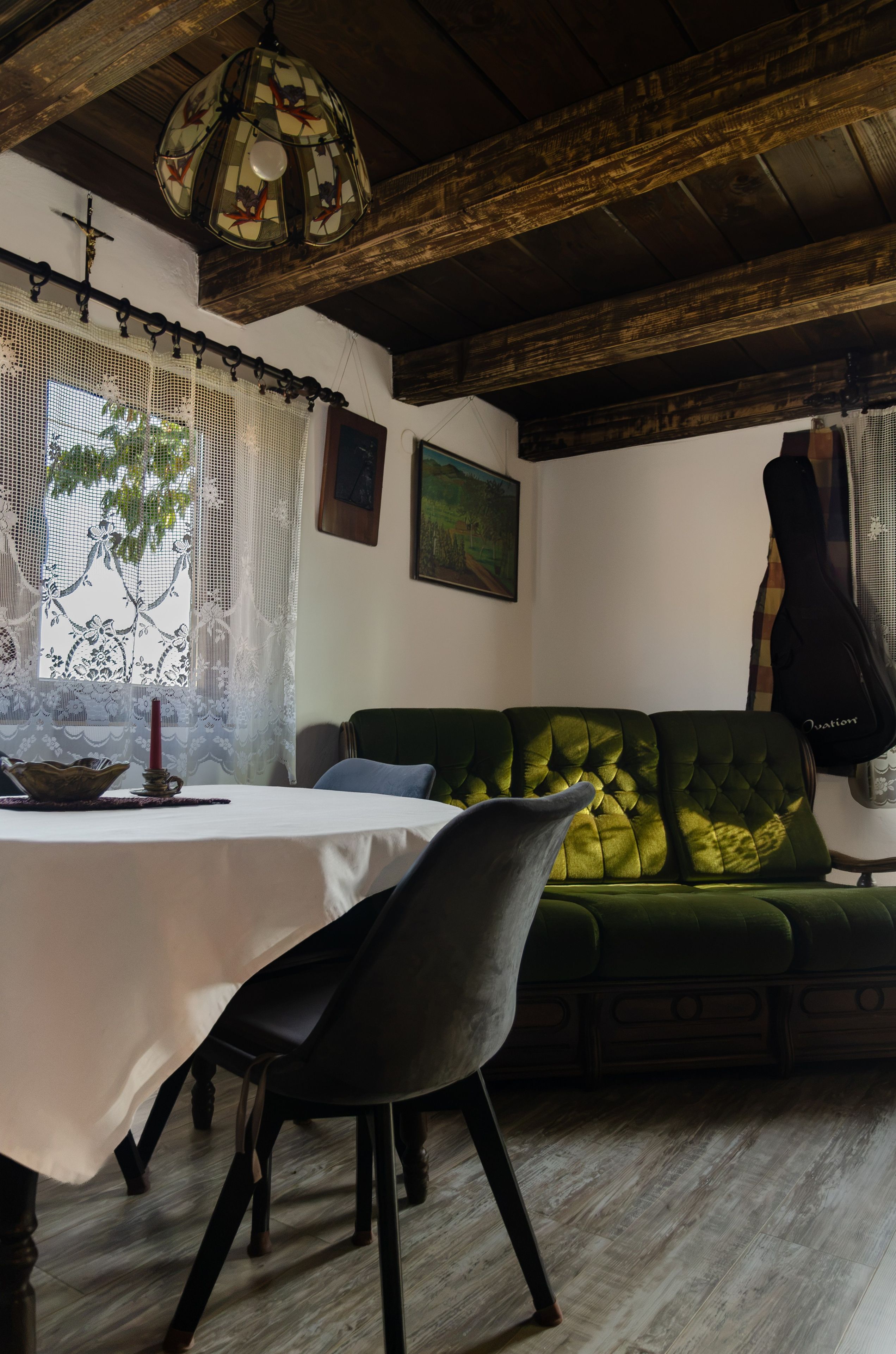 Un comedor con una mesa, sillas, un sofá verde y una lámpara colgante.