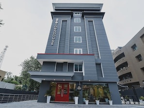 Un edificio moderno con una entrada destacada, un letrero vertical que dice 'OYOTOWNHOUSE' y un amplio piso a nivel con grandes ventanales.