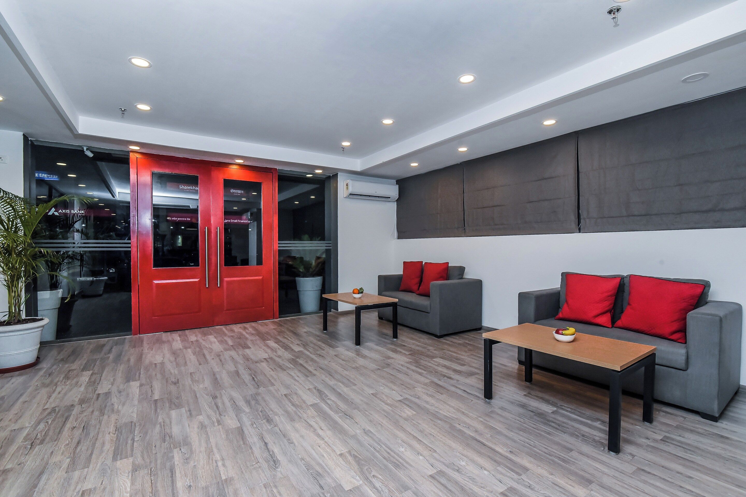 A modern interior with a grey sofa, red cushions, a wooden coffee table, and a potted plant.