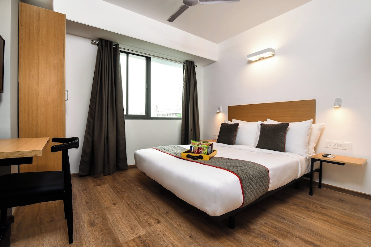 Una habitación de hotel con una cama, mesita de noche, escritorio y una silla.