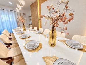 A long dining table set for a meal with white plates, gold accents, and two vases with dried flowers. - Newly Furnished 10BR | South Pool & Spa | Games (Davenport)