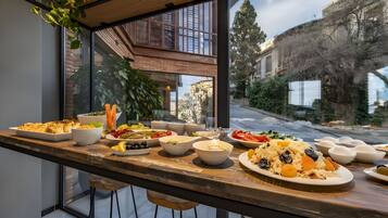 Un tavolo da pranzo con diversi piatti e vista su un edificio attraverso ampie finestre.