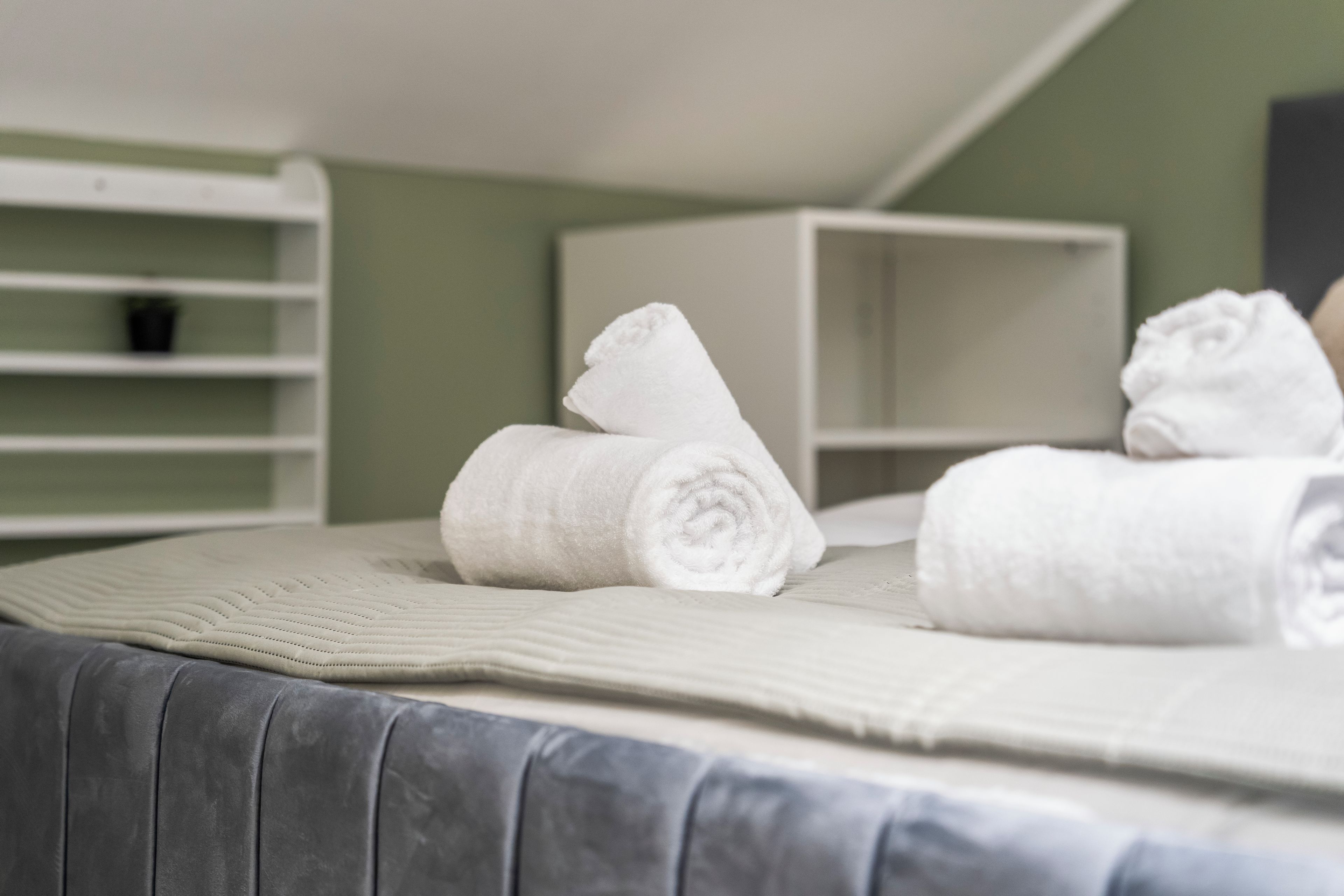 A neatly made bed with rolled white towels and a quilted blanket.
