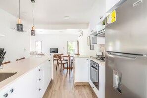 A modern kitchen with a central island, stainless steel appliances, and a dining area with wooden chairs. - Nazar Suites - Unit 2A (Santiago de los Caballeros)
