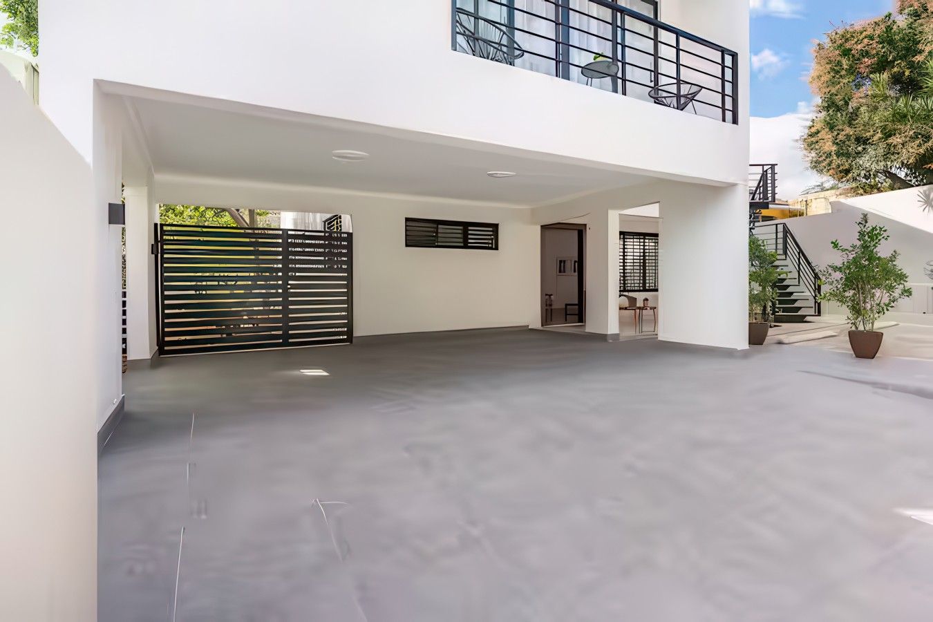 Un vaste espace extérieur couvert, doté d’un design moderne, avec un toit plat et un portail noir.