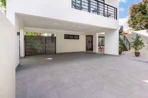 Un vaste espace extérieur couvert, doté d’un design moderne, avec un toit plat et un portail noir.