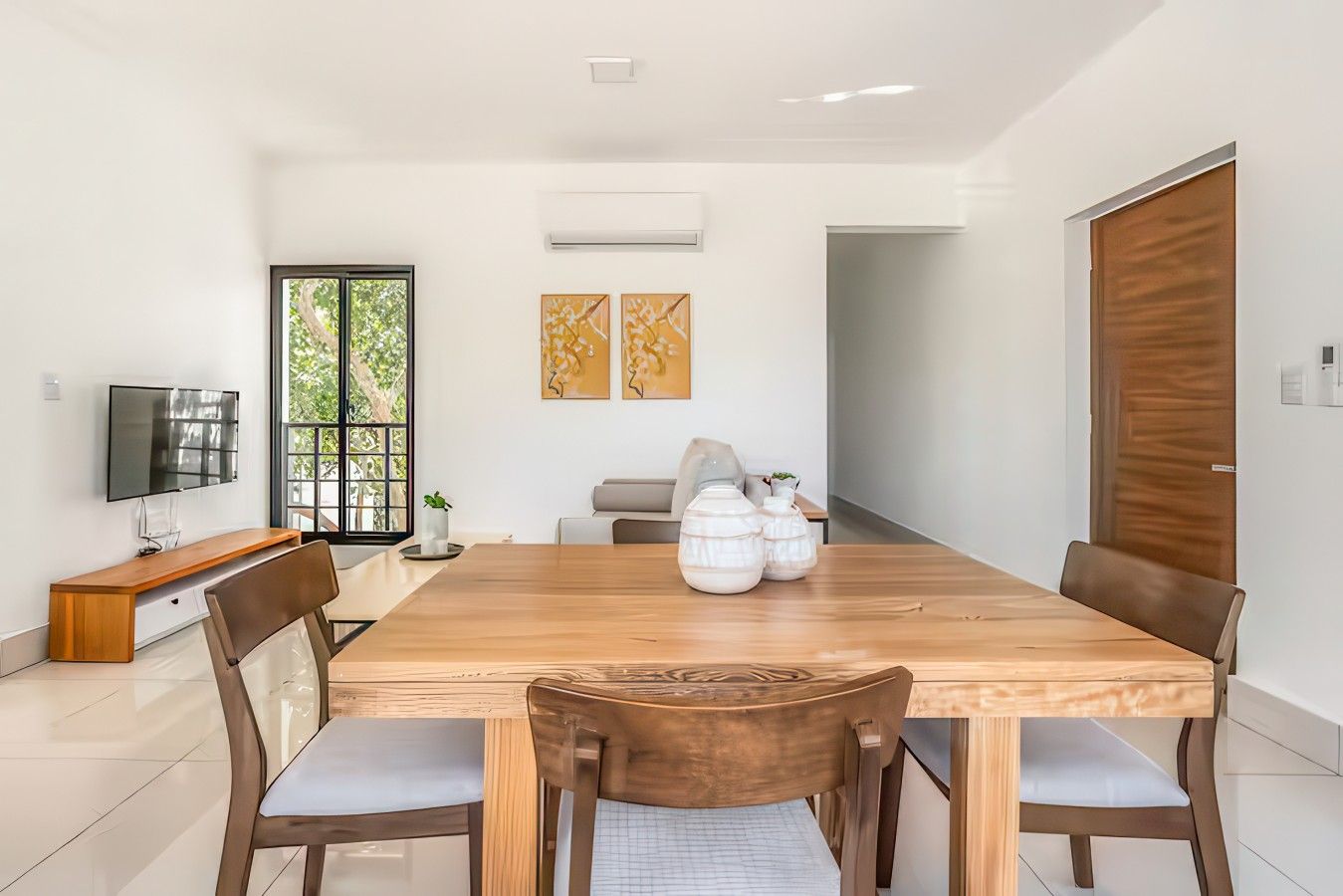 Un espace repas moderne avec une table en bois, des chaises et un téléviseur posé sur un meuble.