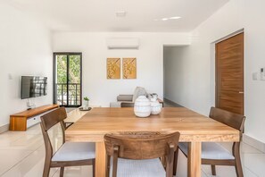 Un espace repas moderne avec une table en bois, des chaises et un téléviseur posé sur un meuble.